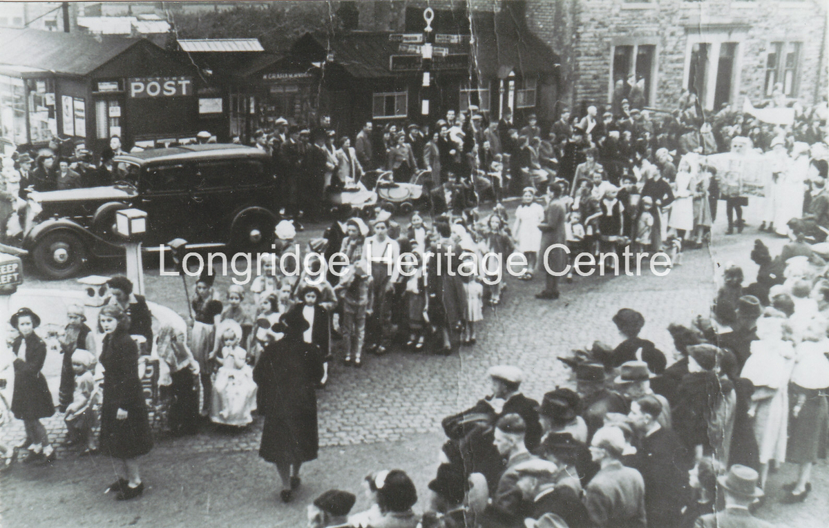 214A - Stone Bridge - A VE or VJ day parade passing Grahams and the chip shop - 1945